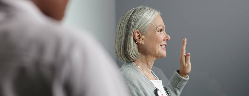 Image of senior woman raising her hand at a hearing evaluation